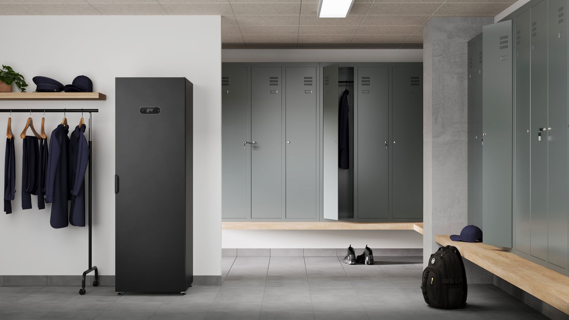 Det svarta Alizé Steaming Cabinet står i ett ljust och modernt omklädningsrum, omgiven av plåtskåp i en grågrön nyans.